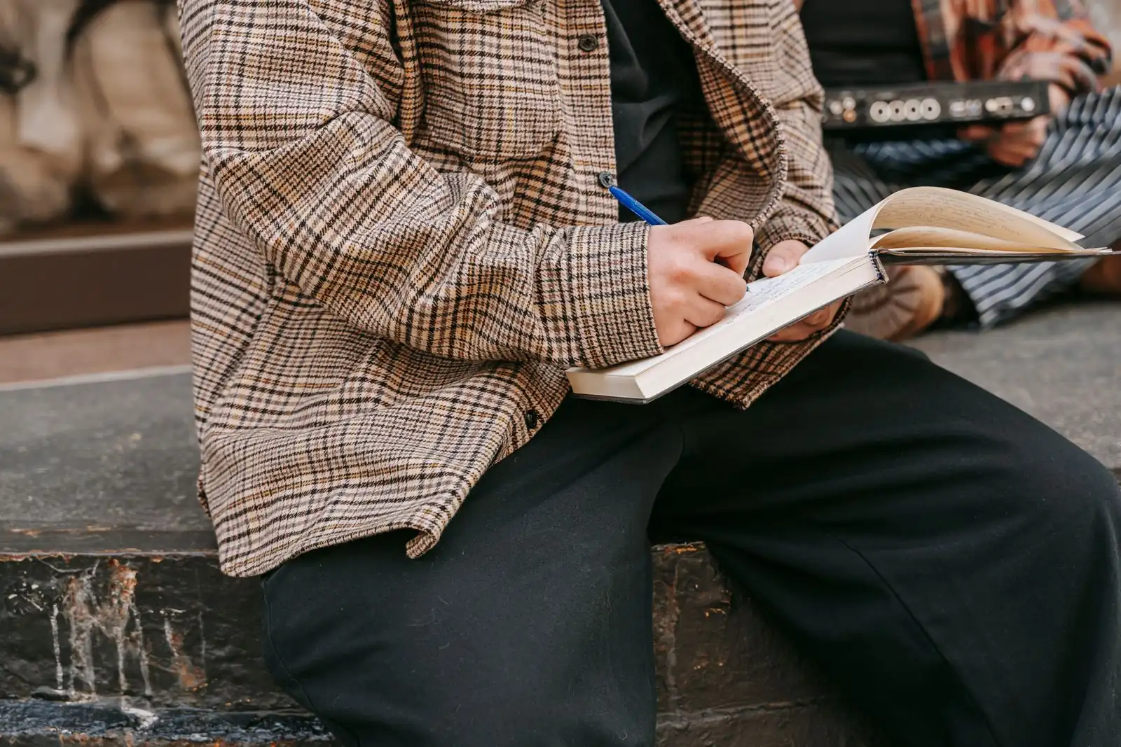 Person writing in a journal outdoors in natural light