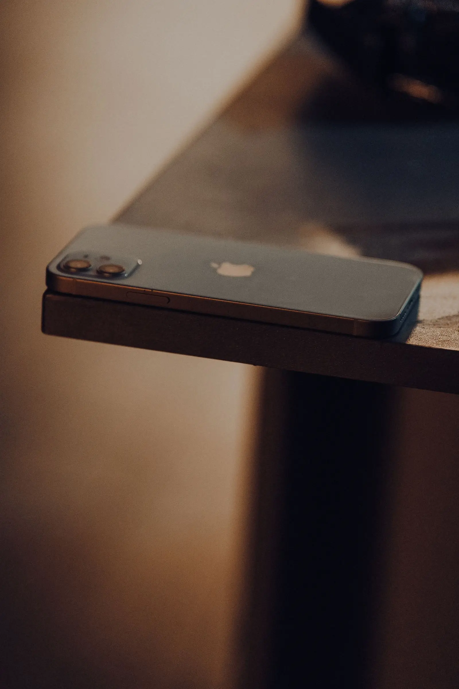 A smartphone lying face down on a wooden table, put aside and out of reach