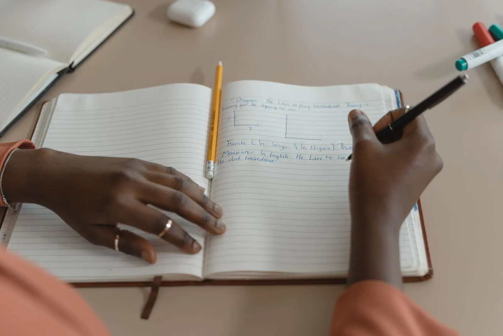 Close-up of hands writing in a lined notebook with a pen