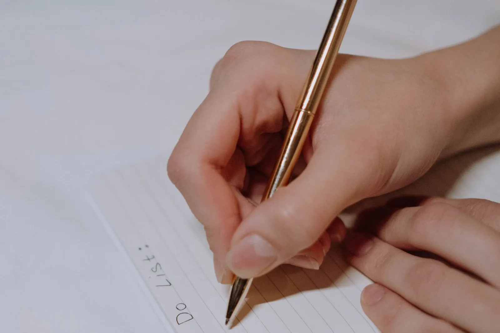 Hands writing a to-do list in a notebook with a pen