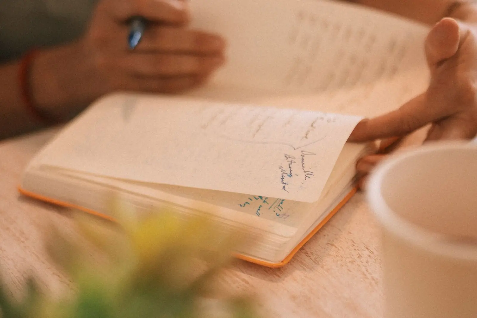 Writing in a notebook beside a cup of coffee in the morning