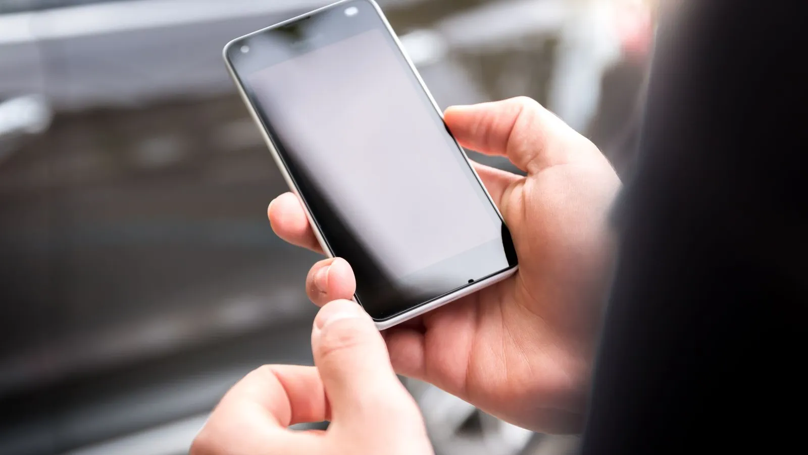 Close-up of hands holding a smartphone during the day